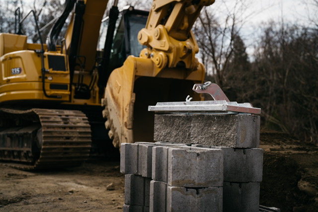 Excavator near stacked concrete blocks on site.
